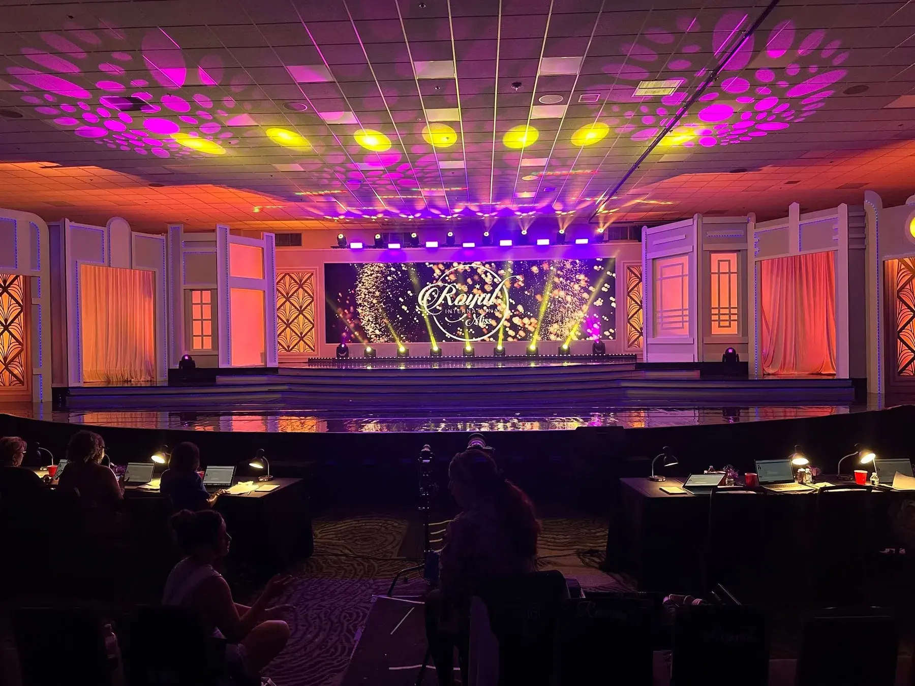 Grand stage with purple and gold lighting and a bright video backdrop