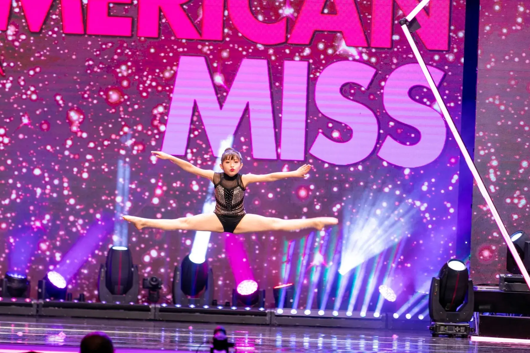 Live performer framed by a vivid video wall and colorful stage lighting