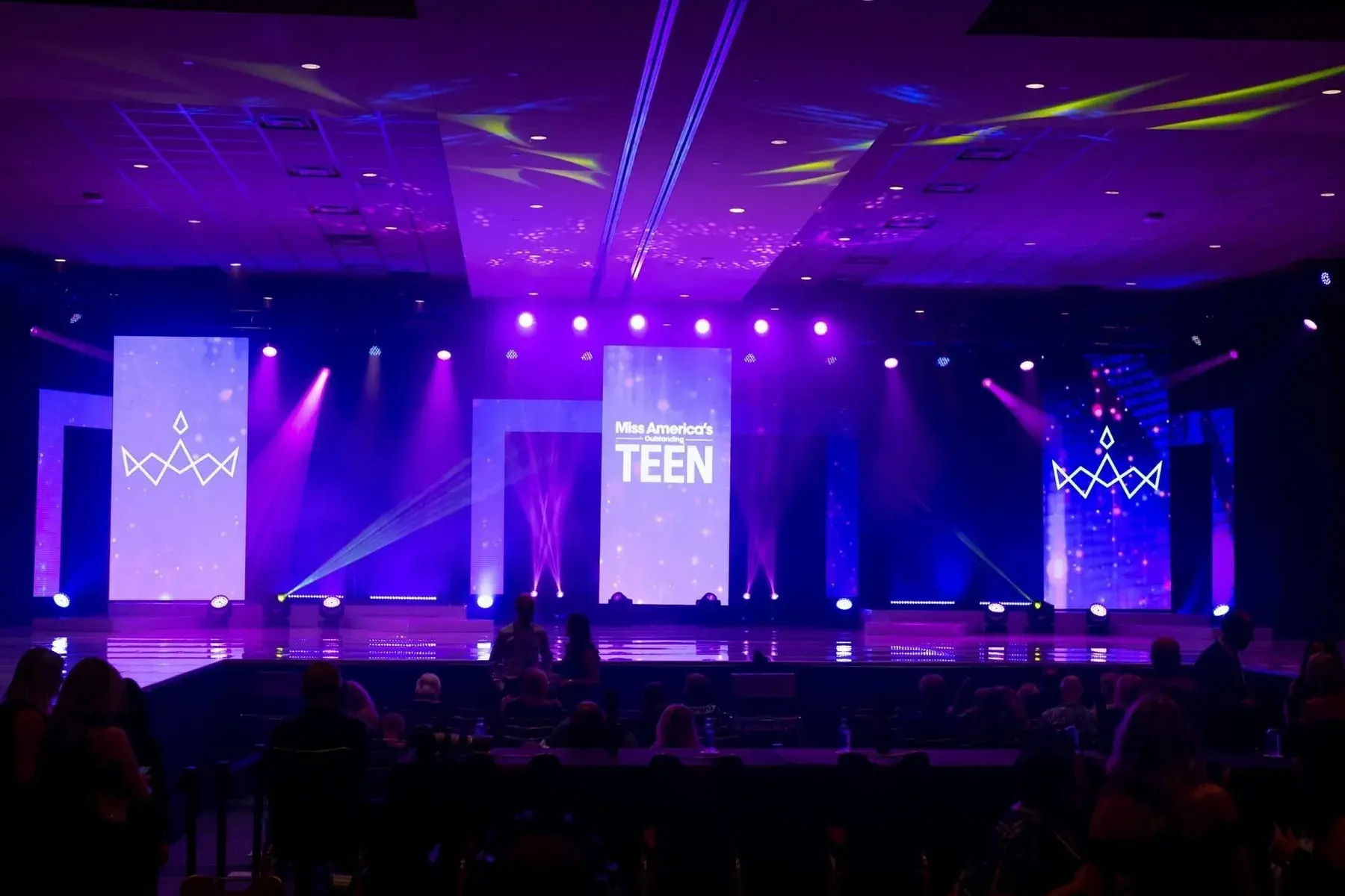 Purple stage with three glowing vertical video displays