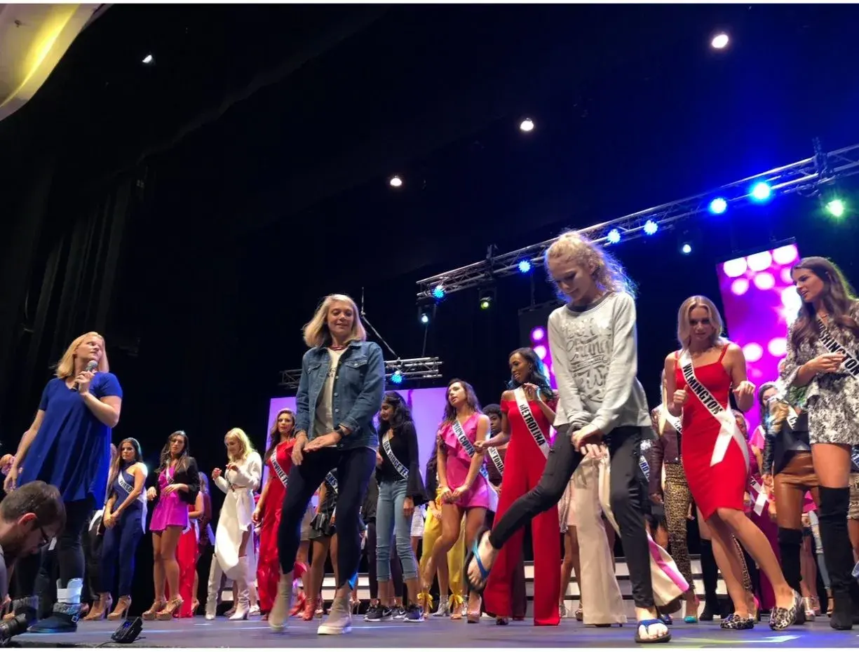 Performers and participants moving across a brightly lit stage
