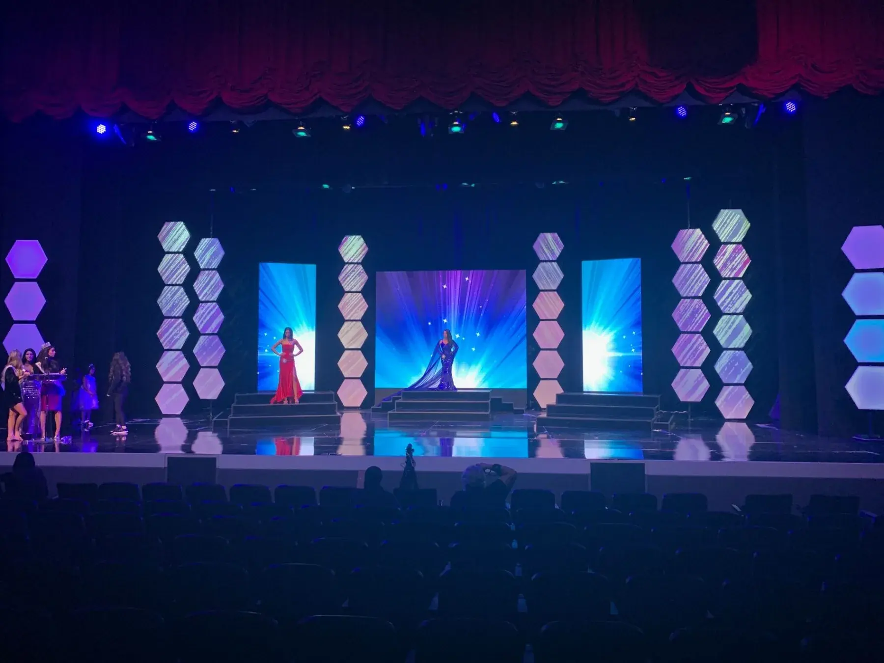 Blue-lit stage with video content and an audience