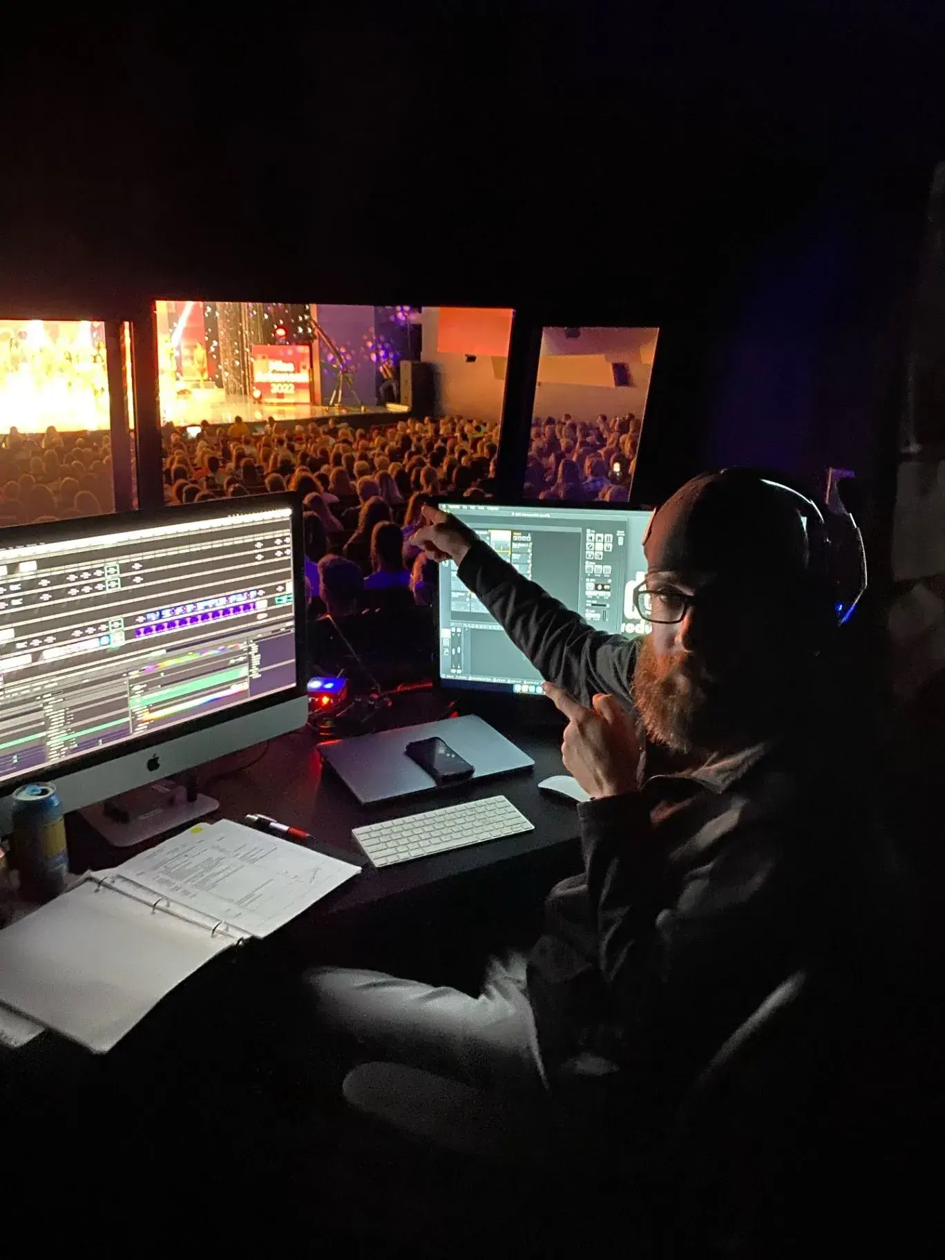 Production operator working in a dark booth with multiple screens